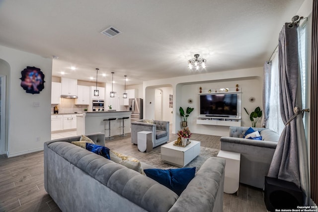 15323 Danae Bnd, San Antonio, TX 78245 - living room featuring arched walkways, light wood-type flooring, baseboards, and recessed lighting
