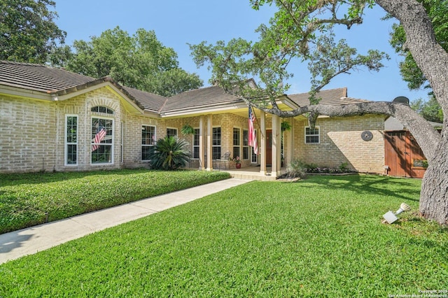 rear view of house featuring a tiled roof, a yard, and brick siding