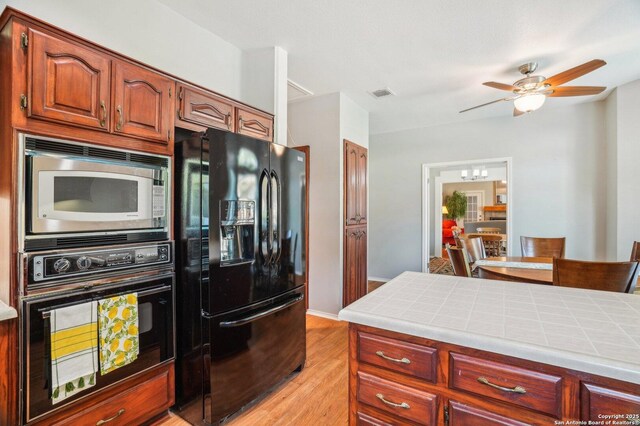 kitchen with black appliances, tile counters, light wood-style floors, and ceiling fan