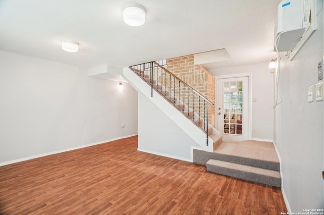 unfurnished living room featuring stairway, wood finished floors, and baseboards
