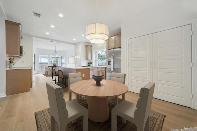 dining room featuring recessed lighting, light wood-style floors, plenty of natural light, and a chandelier