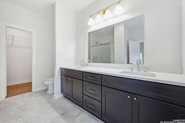 full bath with a shower stall, a spacious closet, double vanity, toilet, and baseboards