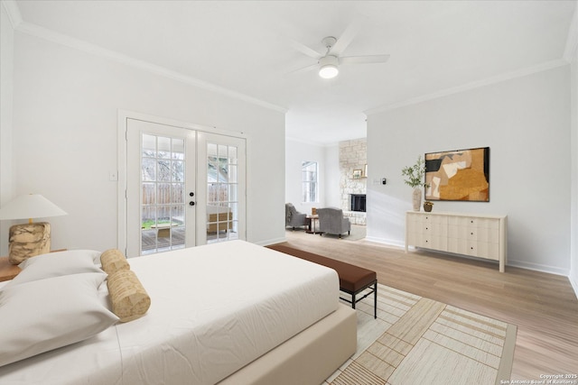 bedroom featuring crown molding, access to outside, light wood-style flooring, french doors, and a stone fireplace