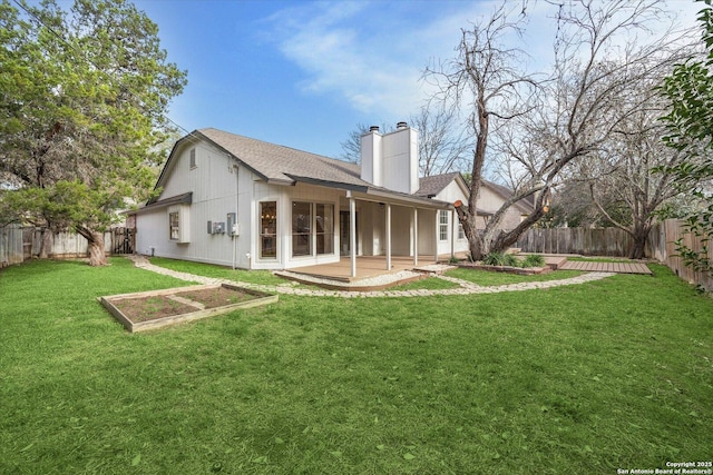 back of property with a chimney, a vegetable garden, a patio, and a shingled roof