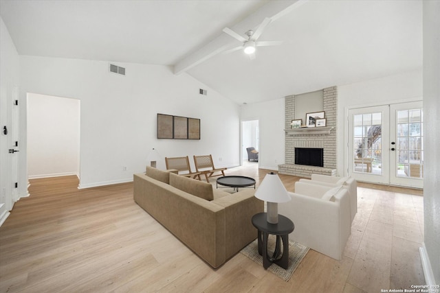 living room featuring light wood-style floors, ceiling fan, a fireplace, baseboards, and french doors
