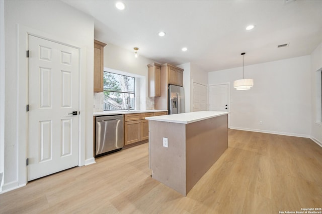 kitchen featuring appliances with stainless steel finishes, light wood-style floors, a kitchen island, light countertops, and recessed lighting