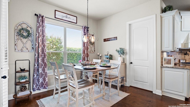 dining area featuring dark wood finished floors, a chandelier, and baseboards