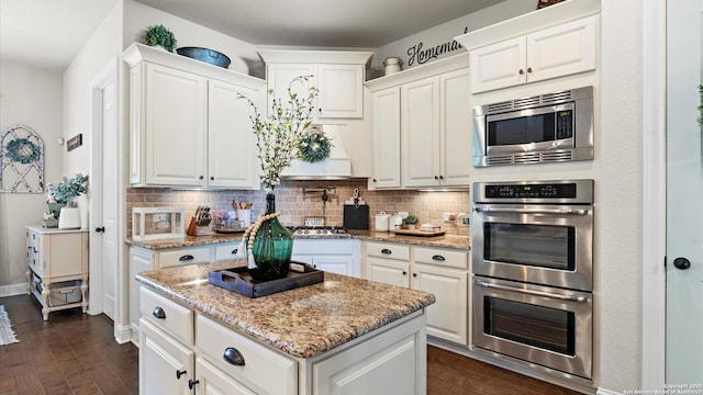 kitchen with stainless steel appliances, decorative backsplash, and light stone counters