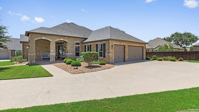 french country home with an attached garage, roof with shingles, brick siding, and concrete driveway