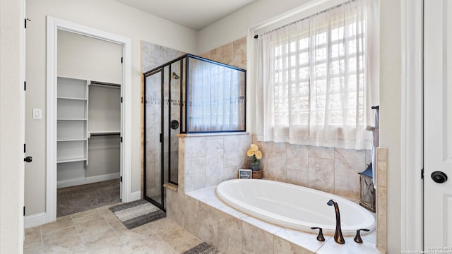 bathroom featuring a spacious closet, a stall shower, a garden tub, and baseboards