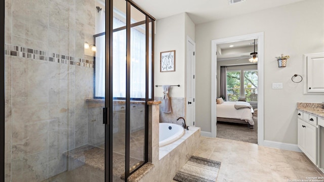 ensuite bathroom featuring vanity, a shower stall, a garden tub, a ceiling fan, and baseboards