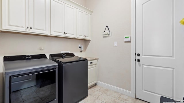clothes washing area featuring separate washer and dryer, cabinet space, baseboards, and light tile patterned floors
