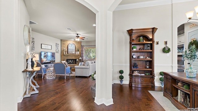 living area with arched walkways, a ceiling fan, and hardwood / wood-style floors
