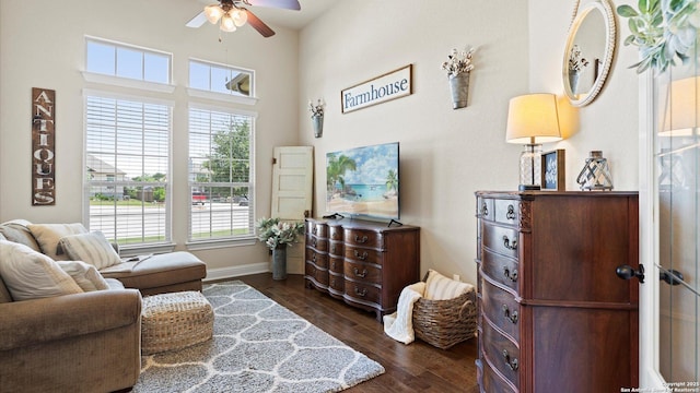 living area with a ceiling fan, dark wood-style floors, and baseboards