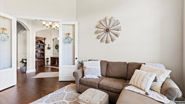 living room featuring arched walkways, wood finished floors, a chandelier, and baseboards