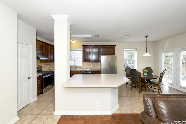 kitchen featuring appliances with stainless steel finishes, under cabinet range hood, light tile patterned floors, light countertops, and tasteful backsplash
