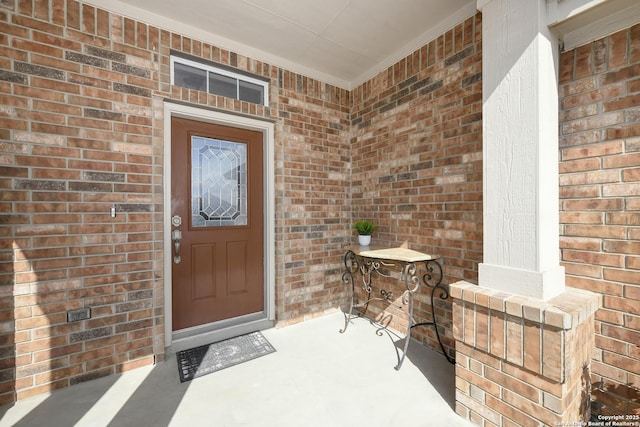 entrance to property featuring brick siding and covered porch