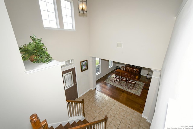 tiled entrance foyer with a high ceiling, a chandelier, baseboards, and stairs