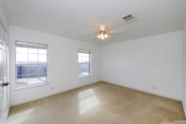 spare room with light colored carpet, a ceiling fan, and baseboards