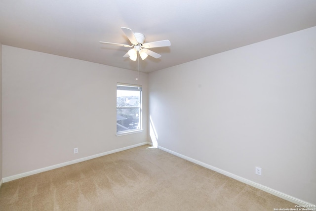 spare room featuring a ceiling fan, light colored carpet, and baseboards