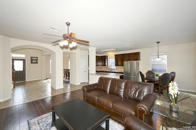 living area featuring arched walkways, baseboards, plenty of natural light, and a ceiling fan
