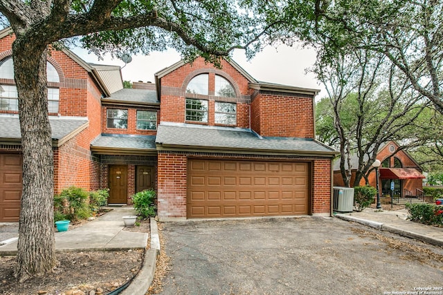 7930 Roanoke Unit 106, San Antonio, TX 78240 - view of front of home with brick siding, central AC, asphalt driveway, a garage, and roof with shingles