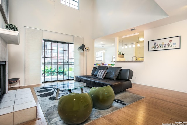 7930 Roanoke Unit 106, San Antonio, TX 78240 - living area featuring wood finished floors, healthy amount of natural light, baseboards, a towering ceiling, and a tile fireplace
