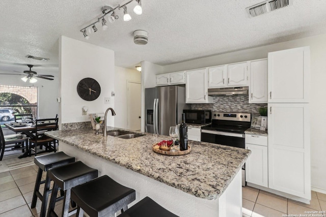 11731 Spring Rain, San Antonio, TX 78249 - kitchen featuring stainless steel appliances, a sink, under cabinet range hood, light tile patterned floors, and a textured ceiling