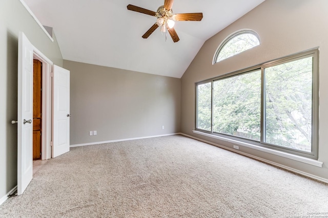 carpeted spare room featuring vaulted ceiling, ceiling fan, and baseboards