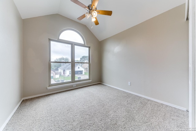 carpeted spare room with a ceiling fan, vaulted ceiling, and baseboards