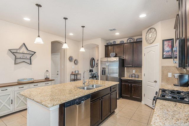 12338 Belfort Pt, Schertz, TX 78154 - kitchen with stainless steel appliances, arched walkways, a sink, light tile patterned floors, and an island with sink