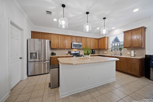 kitchen featuring appliances with stainless steel finishes, a sink, light tile patterned flooring, brown cabinetry, and ornamental molding