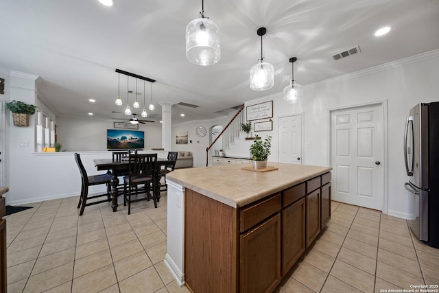 kitchen featuring freestanding refrigerator, light tile patterned flooring, a center island, light countertops, and pendant lighting