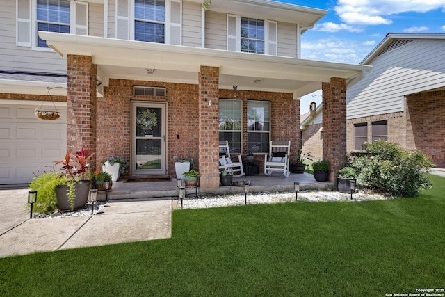 view of exterior entry featuring covered porch, a yard, and brick siding