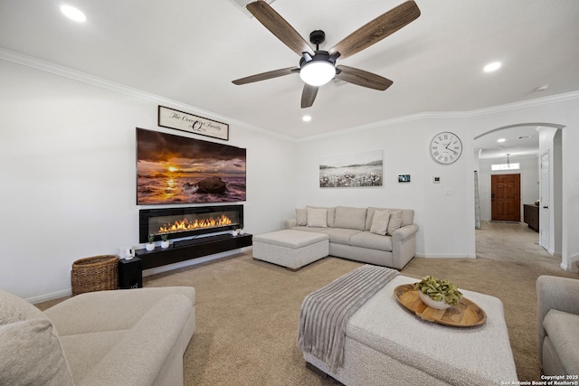 living area featuring arched walkways, recessed lighting, light colored carpet, ceiling fan, and a glass covered fireplace
