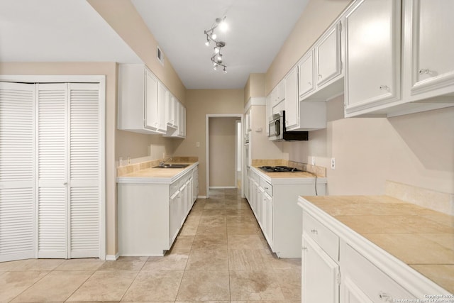 3678 Hidden Unit 504, San Antonio, TX 78217 - kitchen with a sink, baseboards, light countertops, stainless steel microwave, and white cabinets
