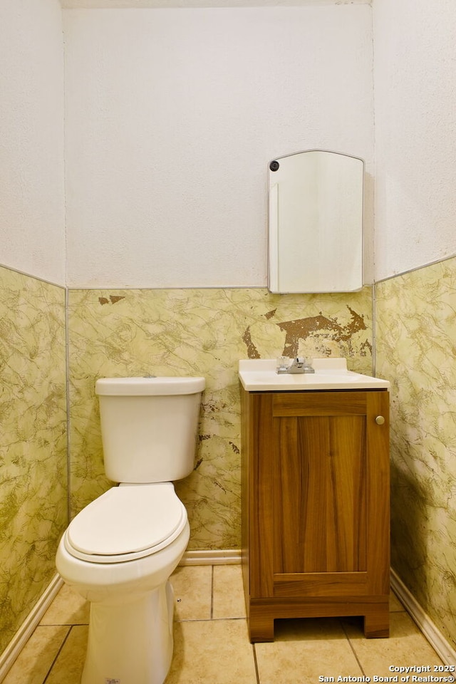 half bath featuring vanity, toilet, tile patterned flooring, and baseboards
