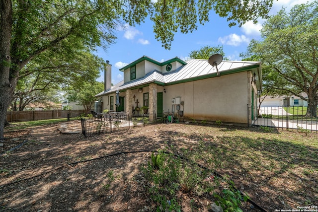 107 River Knl, Castroville, TX 78009 - rear view of house featuring a standing seam roof, metal roof, fence, and stucco siding