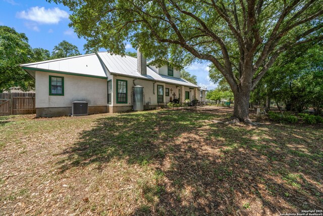 107 River Knl, Castroville, TX 78009 - rear view of property featuring fence, central AC, metal roof, and stucco siding