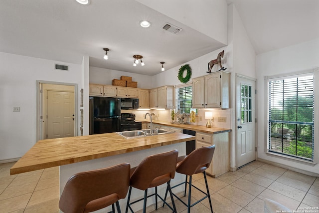 107 River Knl, Castroville, TX 78009 - kitchen featuring black appliances, a sink, wood counters, light tile patterned flooring, and a breakfast bar