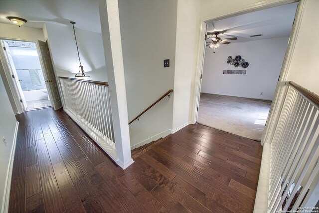 hallway with an upstairs landing, dark wood-style flooring, and baseboards