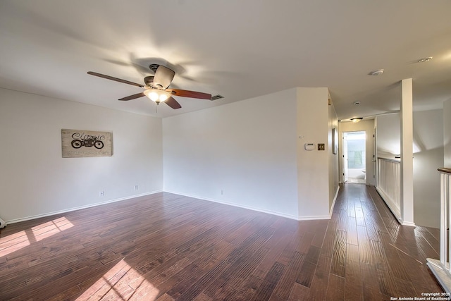 spare room featuring a ceiling fan, dark wood-style floors, and baseboards