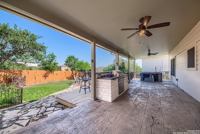 view of patio with exterior kitchen, a deck, area for grilling, a fenced backyard, and a ceiling fan
