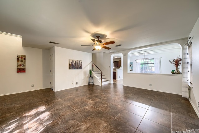 unfurnished living room with arched walkways, ceiling fan, and baseboards