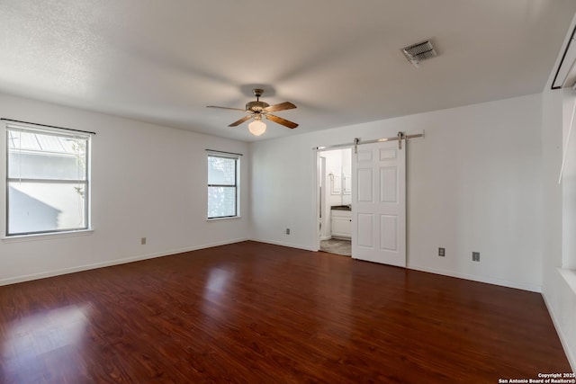 107 Mesa Del Sol, Kerrville, TX 78028 - unfurnished room with a ceiling fan, a barn door, wood finished floors, and baseboards