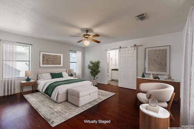 107 Mesa Del Sol, Kerrville, TX 78028 - bedroom featuring a barn door, dark wood-style flooring, ceiling fan, and baseboards