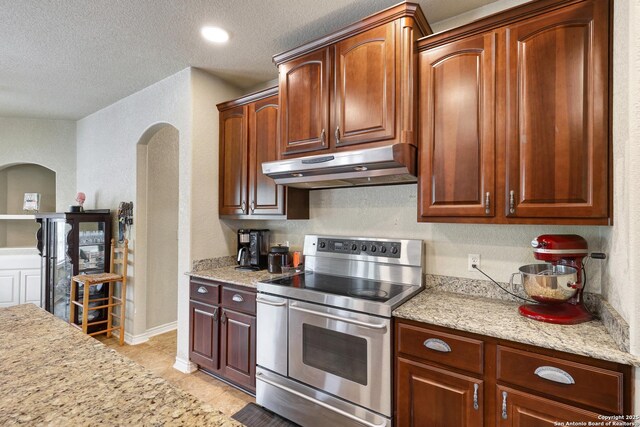201 Oak Rdg, Boerne, TX 78006 - kitchen featuring range with two ovens, under cabinet range hood, arched walkways, a textured ceiling, and a textured wall