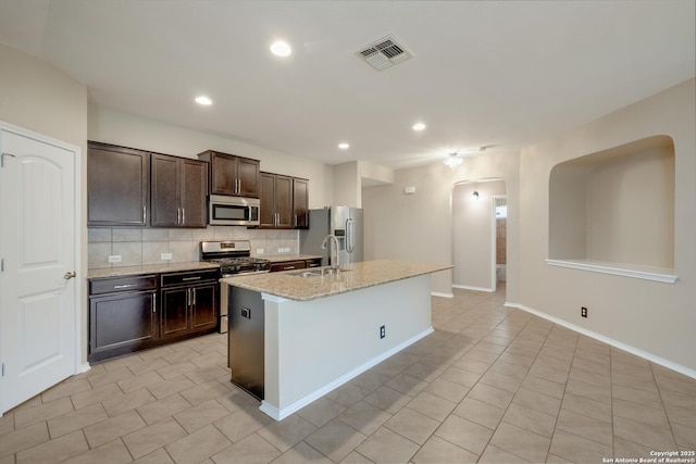 173 Kildeer Crk, San Antonio, TX 78253 - kitchen with appliances with stainless steel finishes, a sink, arched walkways, dark brown cabinetry, and decorative backsplash