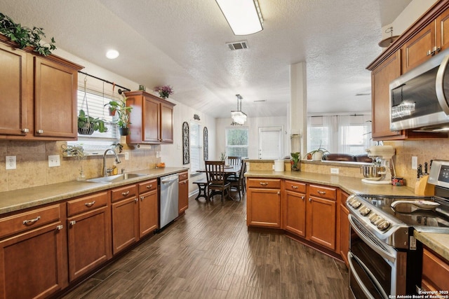7938 Sterling Mnr, Converse, TX 78109 - kitchen with appliances with stainless steel finishes, a sink, brown cabinetry, healthy amount of natural light, and a textured ceiling