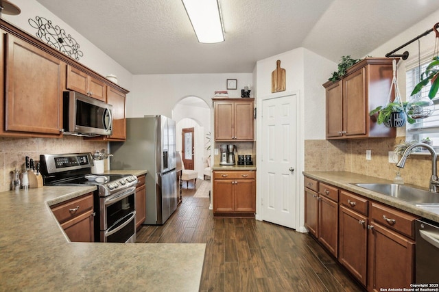 7938 Sterling Mnr, Converse, TX 78109 - kitchen featuring stainless steel appliances, a sink, arched walkways, a textured ceiling, and dark wood finished floors